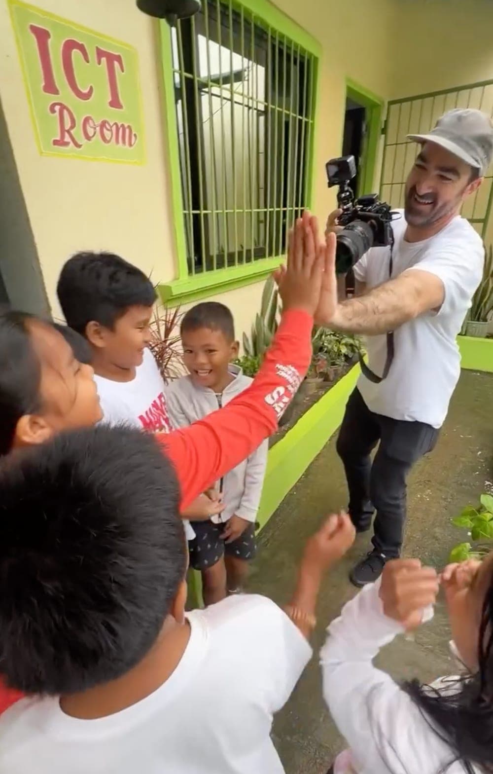 William Graham filming on location, trading high-fives with kids between takes